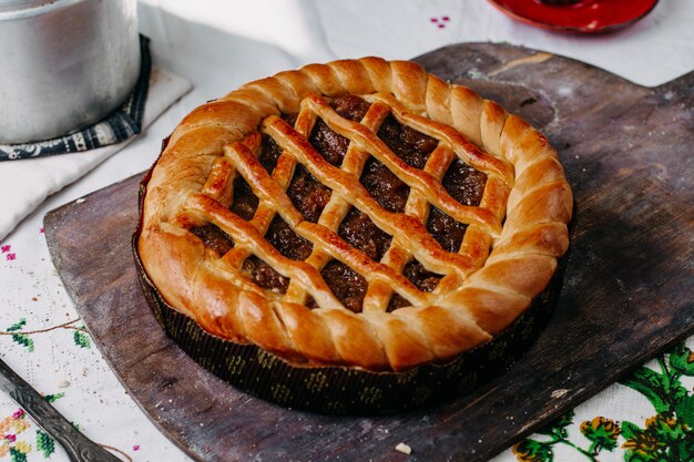 プレッツェルは、茶色の木製の机の上の丸い鍋の中にチョコレートの丸い焼き甘いおいしい茶色のケーキを形成しました