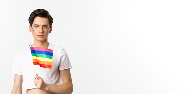 Free photo pride and lgbtq concept waist up shot of attractive anrogynous man holding rainbow flag having glitt
