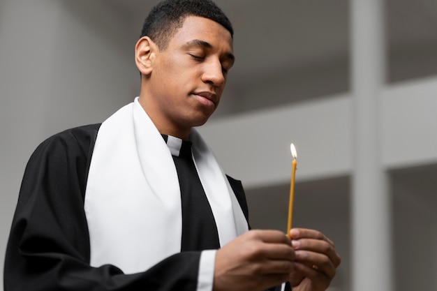 Foto gratuita colpo medio della candela della holding del sacerdote