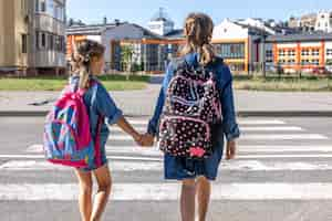 Foto gratuita gli studenti della scuola primaria vanno a scuola tenendosi per mano il primo giorno di scuola tornano a scuola