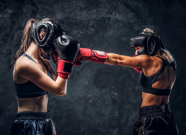 Process of fight between two female boxers in gloves and helmets over dark background.