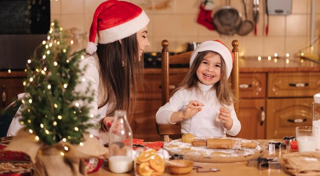 Процесс выпечки мамы и дочки в домашних условиях сырого теста для приготовления рождественского печенья на пряниках