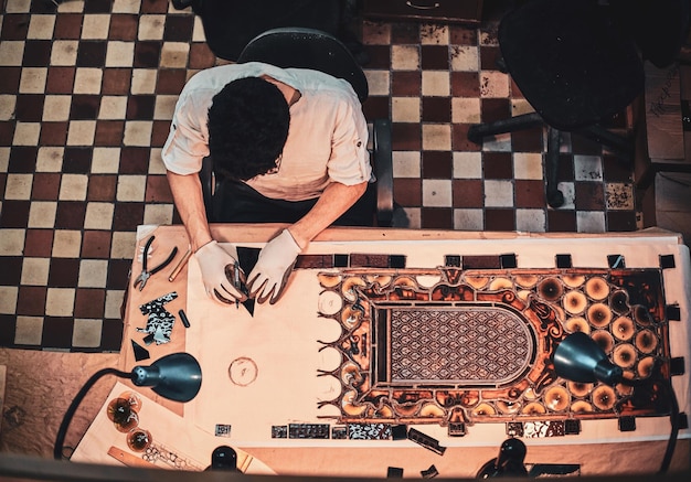 Free photo process of restouration antoque stained glass by expirienced restorer at his workshop. top view, checkered floor at background.