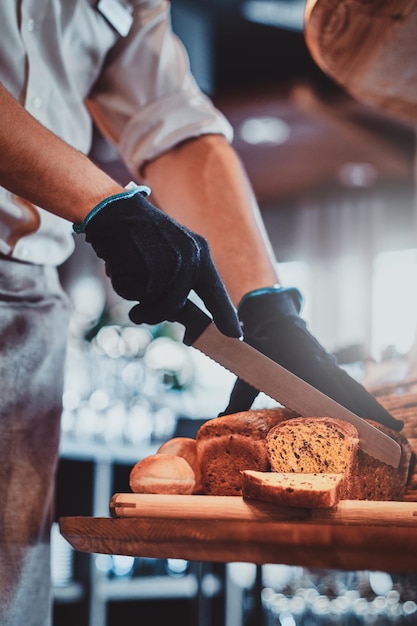 Processo di affettatura della pagnotta con semi in cucina per la colazione in un hotel elegante dal fornaio.