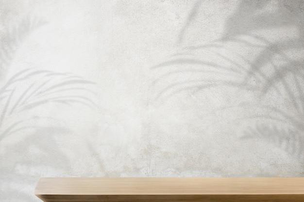 Product backdrop, empty wooden table with concrete wall and plant shadow