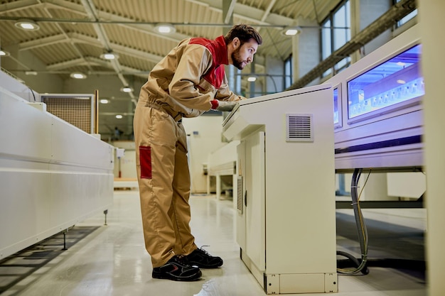 Production line worker operating automated machine at woodworking industrial facility