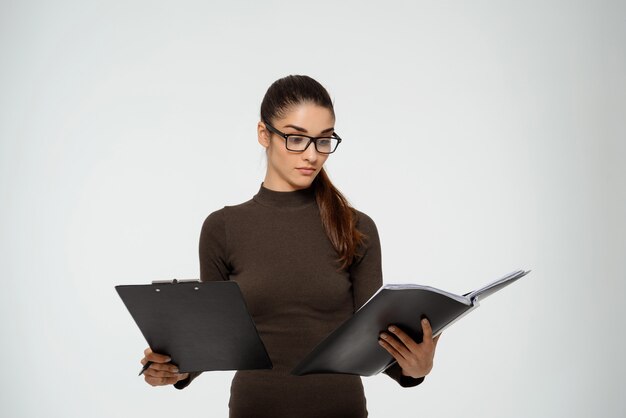 Free photo productive smart businesswoman studying report, hold documents