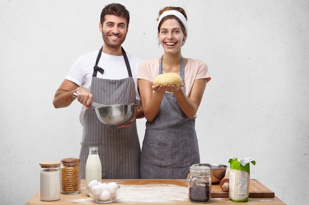 Products, food, cuisine and cooking concept. Portrait of happy positive young European couple baking homemade bread
