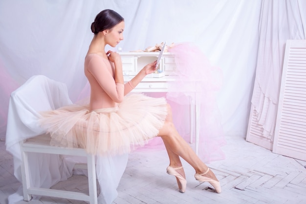Professional ballet dancer looking in mirror on pink