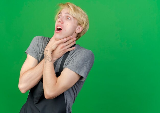 Free photo professional barber man in apron choking holding hands around his neck in panic