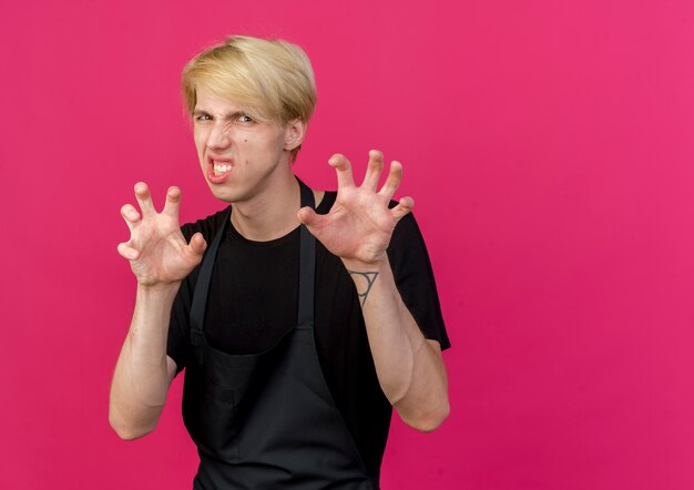 Professional barber man in apron making cat claw gesture with hands 