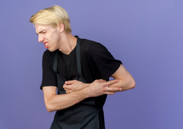 Professional barber man in apron touching his hand feeling pain 