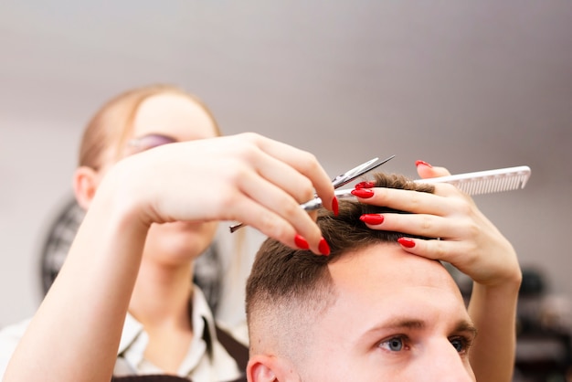 Professional barber shop worker doing her job close-up