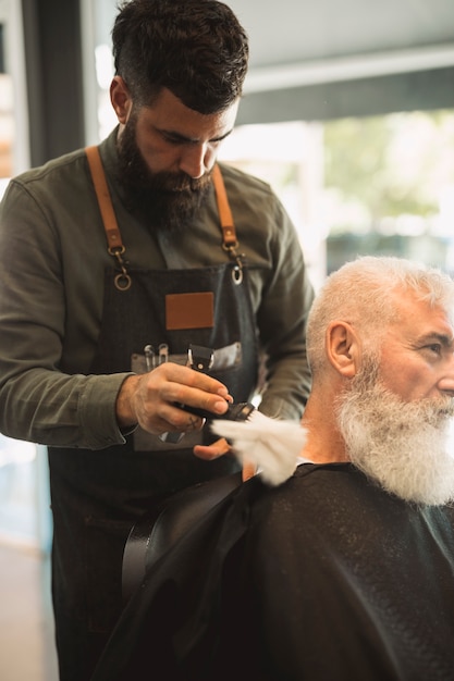 Professional barber with brush preparing neck hair for shaving