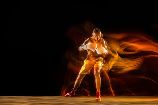Professional boxer training isolated on black studio background in mixed light