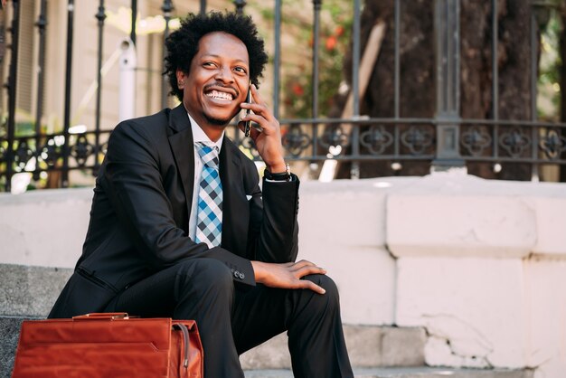 Professional businessman talking on the phone while sitting on stairs outdoors. Business and technology concept.