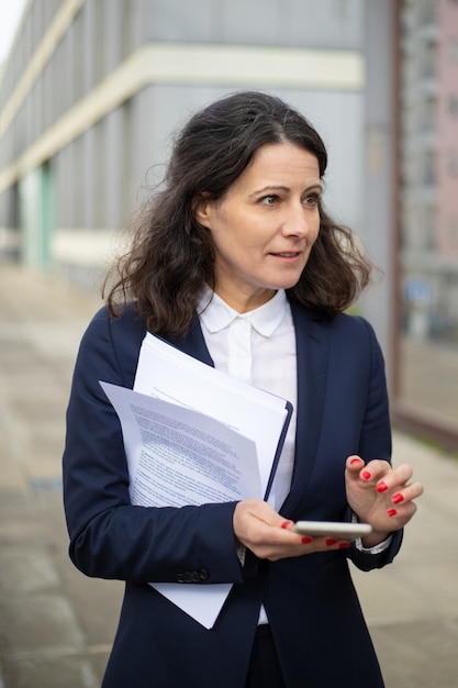 Professional businesswoman with smartphone and papers