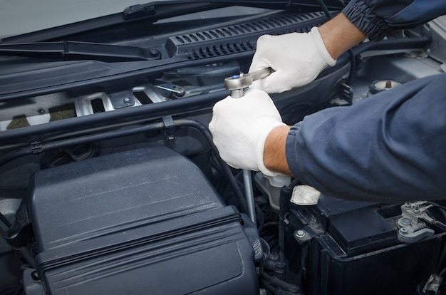 Professional car mechanic in repair shop fixing car