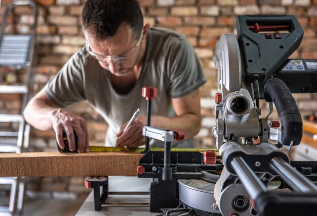 A professional carpenter works with a circular saw miter saw in a workshop.