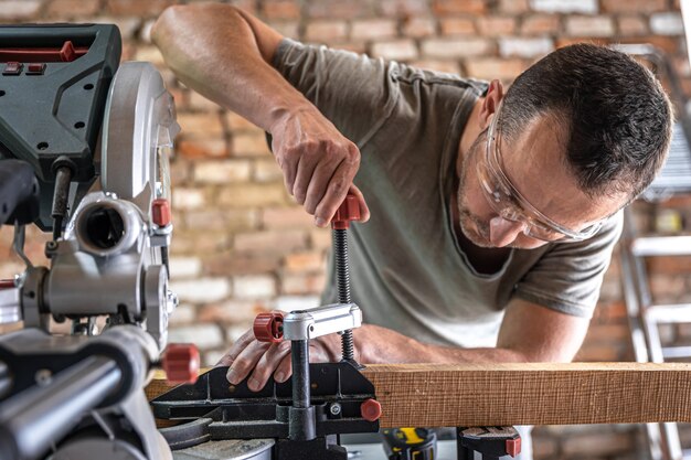 A professional carpenter works with a circular saw miter saw in a workshop.