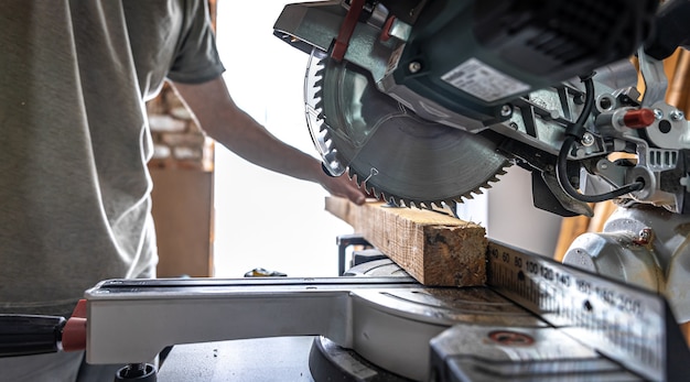 A professional carpenter works with a circular saw miter saw in a workshop.