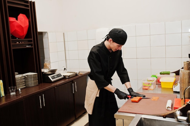 Professional chef wear in black making sushi and rolls in a restaurant kitchen of japanese traditional food