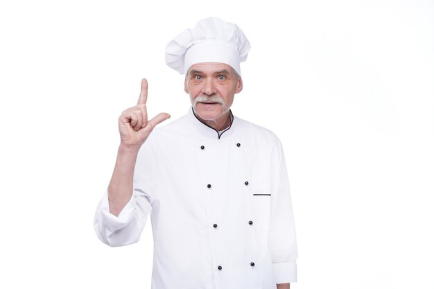 Professional chef in white uniform and hat, on white wall