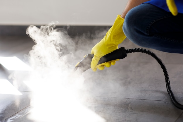Professional cleaning service person using steam cleaner in office