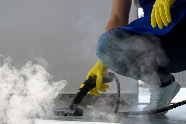 Professional cleaning service person using steam cleaner in office