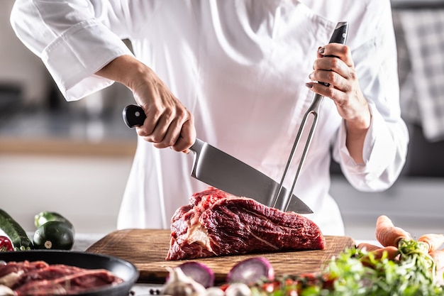 まな板の上で赤身の肉を切るためにシェフが使用するプロのカトラリー。 Premium写真