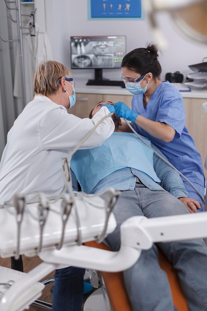 치과 진료실에서 치과 상담을 하는 동안 구강 위생에 대해 논의하는 치아 감염을 분석하는 환자 단튜어를 확인하는 전문 치과 팀. 구강 의학의 개념