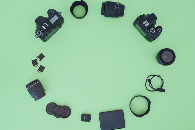 Professional digital camera and accessories arranged over green background