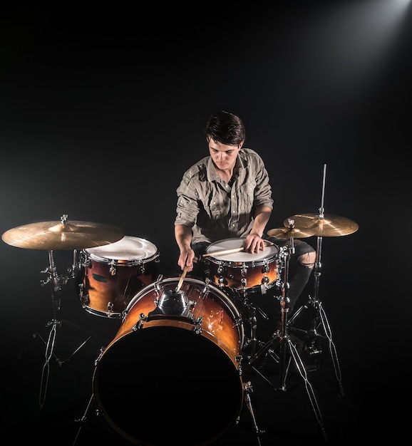 Free photo professional drummer playing on drum set on stage on the black background with drum sticks and vintage look. top view. smoke effect