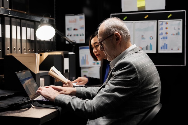 Foto gratuita un uomo d'affari anziano e un assistente asiatico controllano i dati analitici amministrativi in un ufficio di archivio.