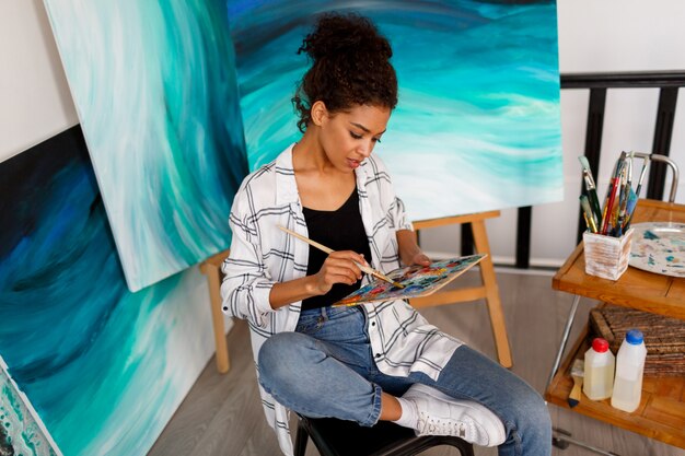 Professional female artist painting on canvas in studio. Woman painter at her  workspace.