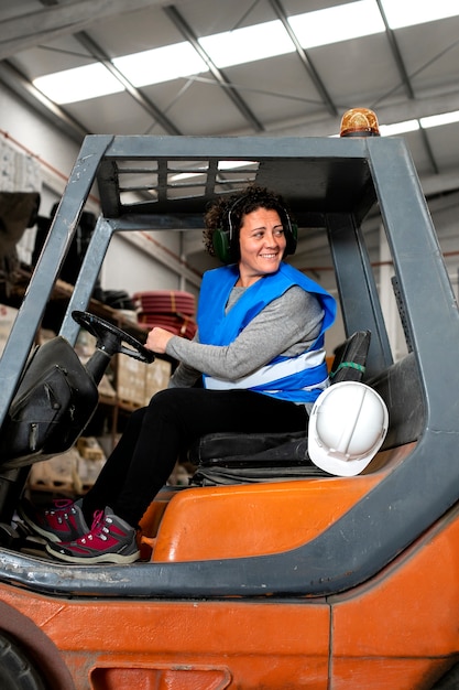Free photo professional female driver operating forklift vehicle
