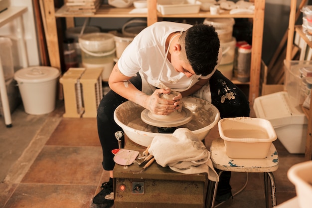 Professional female potter making pot in pottery workshop