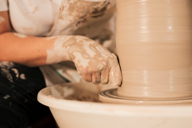 プロの女性陶工が陶芸家のホイールに粘土を平滑化
