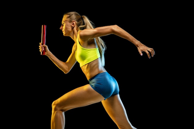 Professional female relay racer training isolated on black studio background in neon light. Free Photo