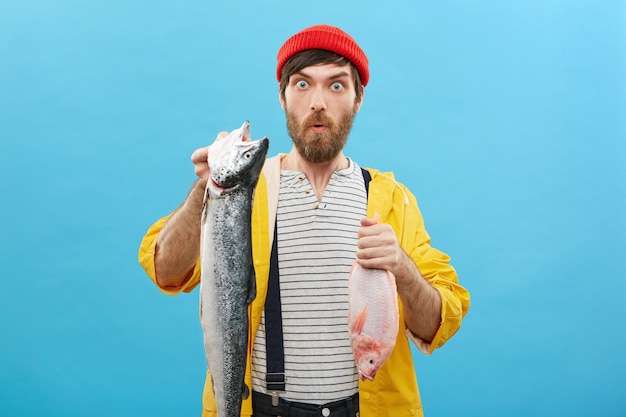 Foto gratuita pescatore professionista che tiene due pesci nelle mani che rallegrano il suo successo