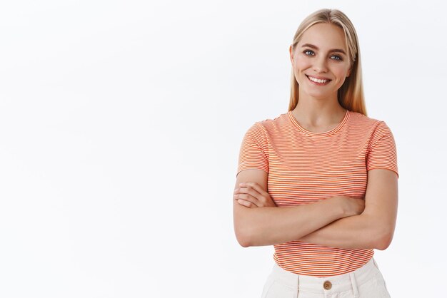 Professional goodlooking caucasian blond woman in striped tshirt cross hands chest and smiling pleased looking confident and ready helpout friend standing white background Copy space
