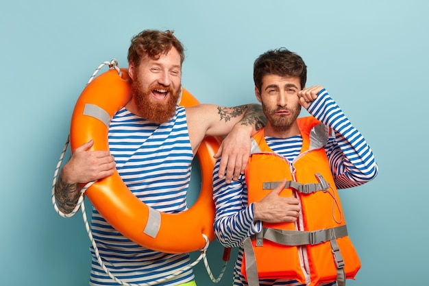 Free photo professional guys posing at the beach with lifejacket and lifebuoy