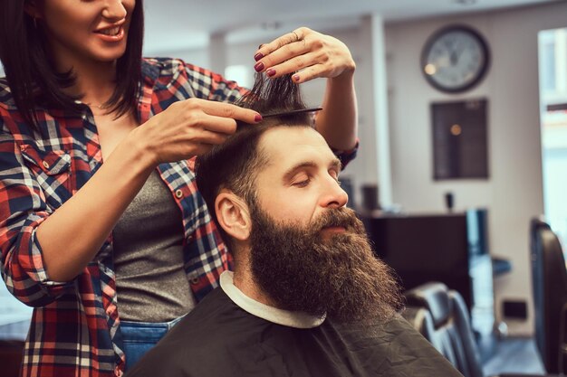 理髪店で櫛でヘアスタイルを作るプロの美容師。