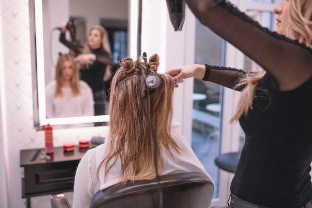 Professional hairstylist setting hair of client