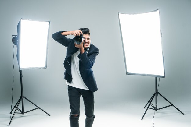 Professional indian young photographer taking photos in studio with leight