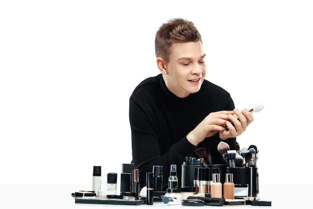 Free photo professional makeup artist with tools isolated on white studio background. the man in female proffesion. gender equality concept