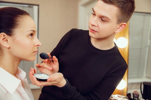 Professional makeup artist working with beautiful young woman.