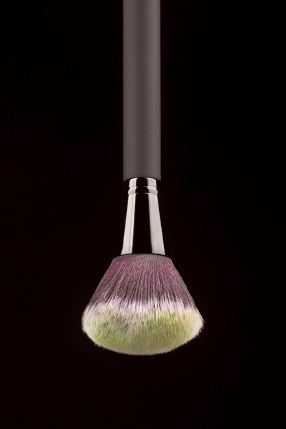 Professional makeup brush with yellow powder on black background