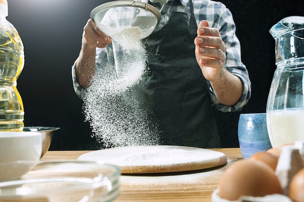 プロの男性料理人が小麦粉で生地を振りかける