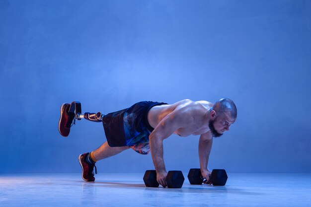 Professional male sportsman with leg prosthesis training with dummbells